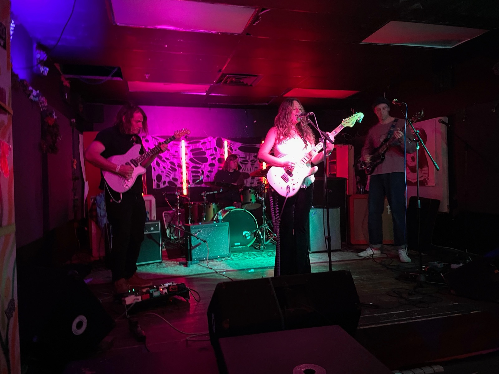 Radar Gold on stage in pink light: two guitarists and a bassist at the front, the drummer behind them.