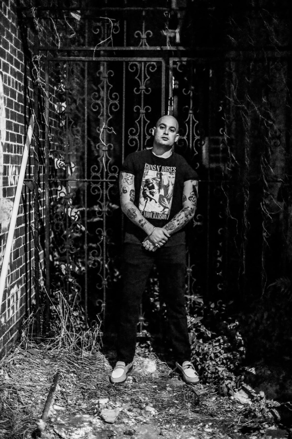 Muddy Marshall standing in front of an iron gate at night, in black and white.